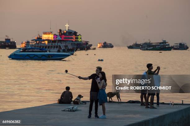 This photo taken on March 29, 2017 shows a couple taking a selfie from a jetty off Beach Road during the late afternoon in Pattaya. Two hours east of...