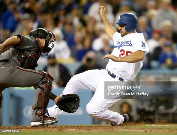 Rob Segedin of the Los Angeles Dodgers slides safely at home past the tag of Jeff Mathis of the Arizona Diamondbacks during the second inning of a...