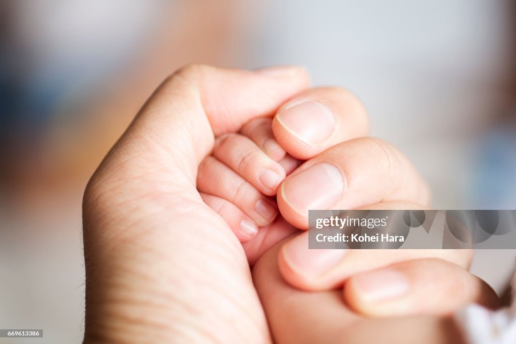 Father's hand holding his baby's hand
