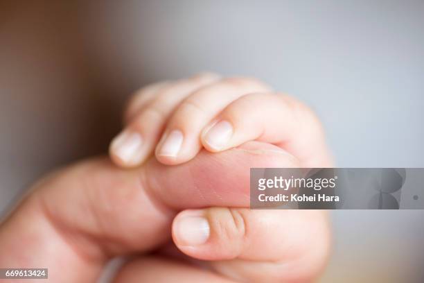 baby's hand holding her father's finger - baby hands ストックフォトと画像