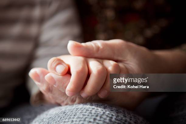 a senior woman's hand holding a boy's hand - darsi la mano foto e immagini stock