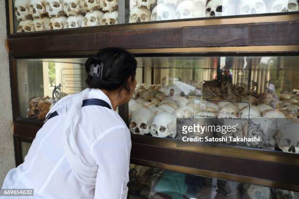 Woman looks at human skulls displayed in a memorial tower at the Choeung Ek killing fields during a memorial service to mark the 42nd anniversary of...