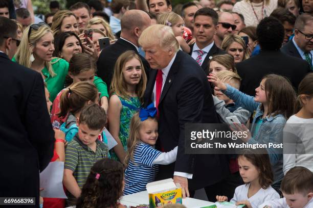 Young girl hugs President Donald Trump after makes cards for members of the military at a craft table during the 139th Easter Egg Roll on the South...