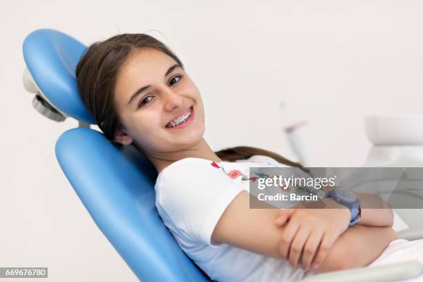歯科医のオフィスで彼女のかっこを浮かべてかわいい十代の少女 - orthodontics ストックフォトと画像