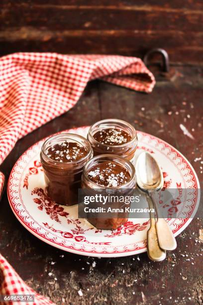 dark chocolate mousse with freshly shredded coconut in jars on a wooden table, selective focus - chocolade mousse stockfoto's en -beelden