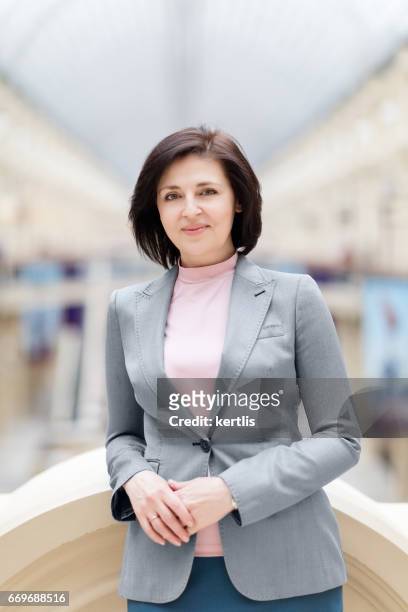 zakenvrouw 50 jaar oud in een grijze jas - 50 54 years stockfoto's en -beelden