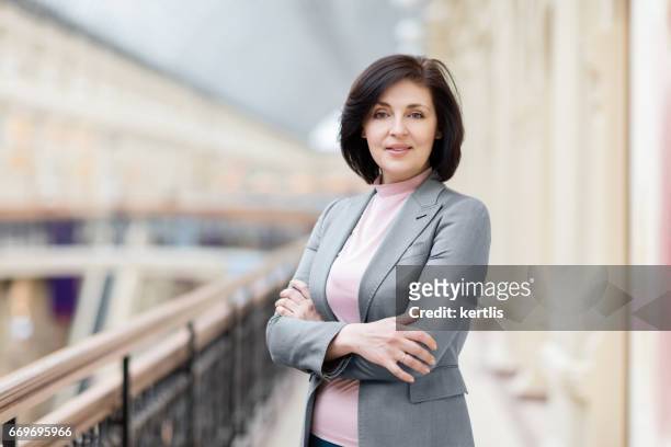 zakenvrouw 50 jaar oud in een grijze jas - 50 54 years stockfoto's en -beelden