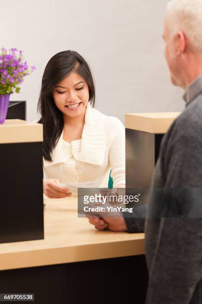 aziatische vrouw bank teller serveren van een klant op de retail bank teller - bank counter old stockfoto's en -beelden