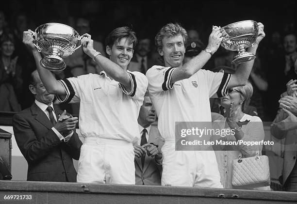 Australian tennis players Todd Woodbridge and Mark Woodforde hold up the trophies after winning the Men's doubles final at the Wimbledon Lawn Tennis...