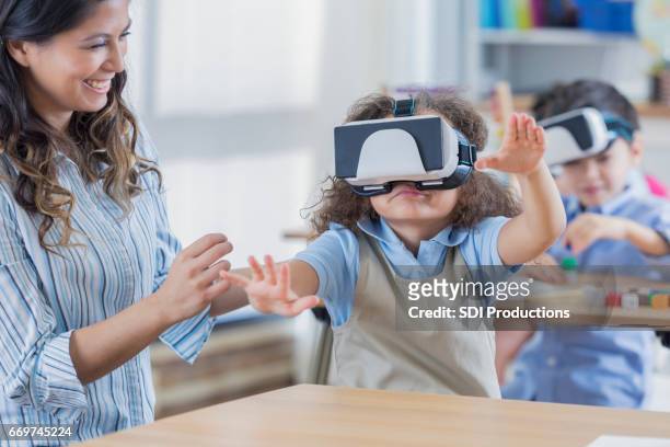 little girl uses virtual reality goggles at school - virtual reality classroom stock pictures, royalty-free photos & images