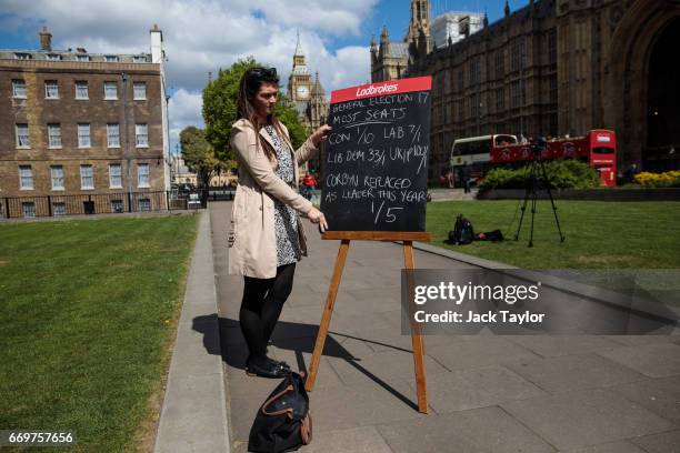 Betting company employee holds up betting odds on a blackboard in College Green outside the Houses of Parliament on April 18, 2017 in London,...