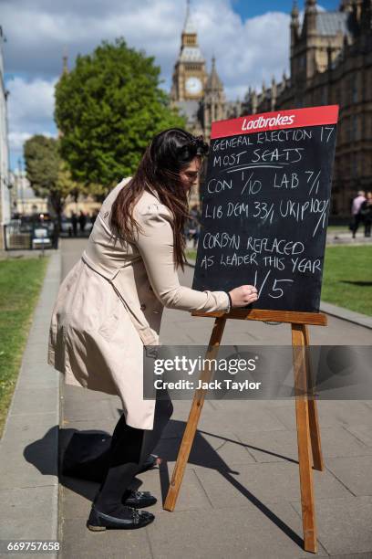 Betting company employee writes betting odds on a blackboard in College Green outside the Houses of Parliament on April 18, 2017 in London, England....