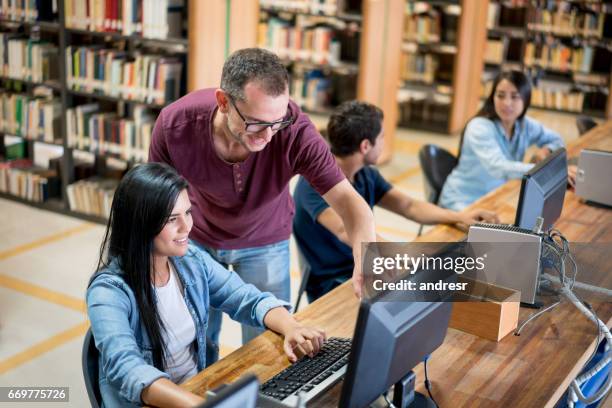 teacher helping student at the library - librarian stock pictures, royalty-free photos & images
