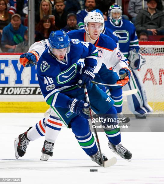 Leon Draisaitl of the Edmonton Oilers looks on as Jayson Megna of the Vancouver Canucks skates up ice with the puck during their NHL game at Rogers...