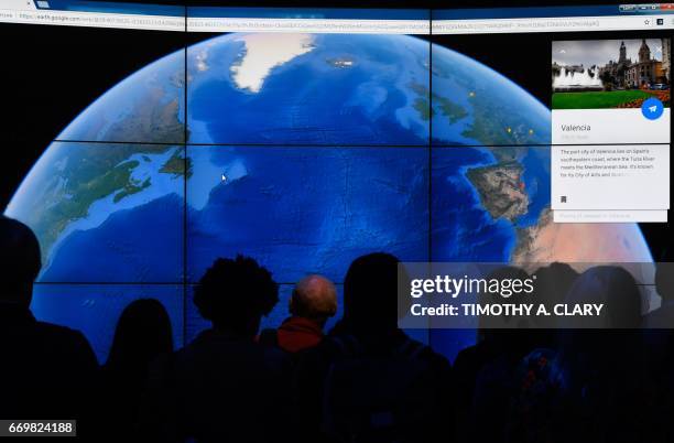 People look at a Google Earth map on a screen as Google Earth unveils the revamped version of the application April 18, 2017 at a event at New York's...