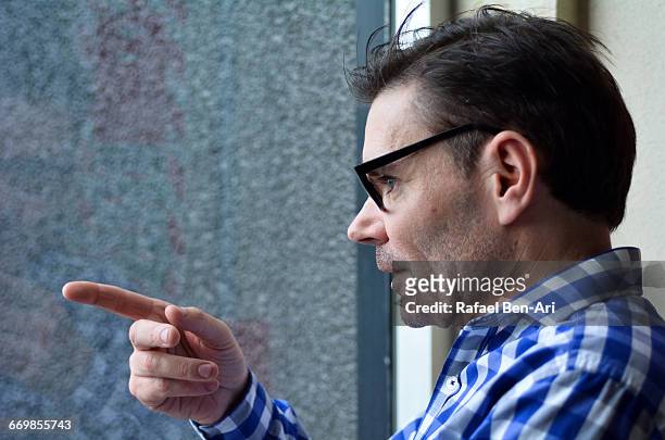 man curiously looks outside a window - photohui stock pictures, royalty-free photos & images