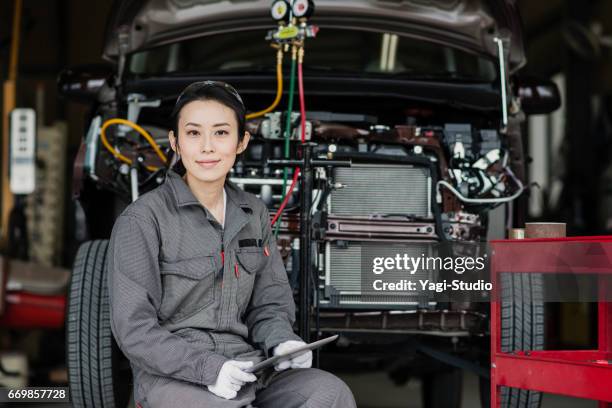 自動でデジタル タブレットで破損した車を検査女性メカニック修理ガレージ - coveralls ストックフォトと画像