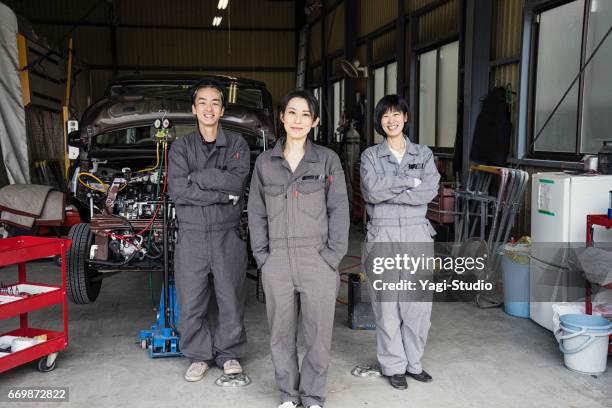 自動車修理工場で作業を行うメカニックのチーム - coveralls ストックフォトと画像