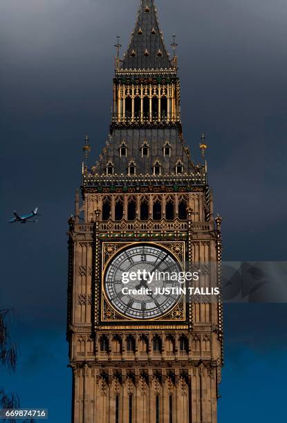 Passenger jet flys behind the clock face of the Elizabeth Tower , commonly referred to as Big Ben, in Westminster, central London on April 18, 2017....