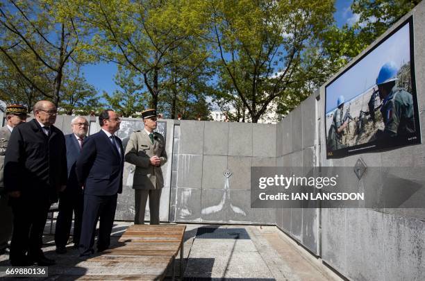 French President Francois Hollande and Defense Minister Jean-Yves Le Drian tours an exhibition of pictures of French military operations taken by...