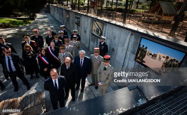 French President Francois Hollande and Defense Minister Jean-Yves Le Drian tours an exhibition of pictures of French military operations taken by...