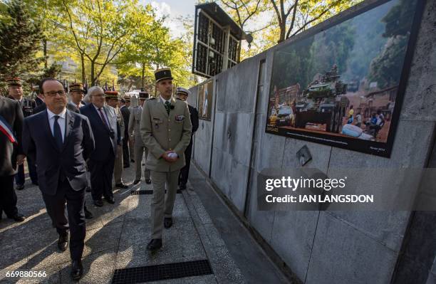 French President Francois Hollande tours an exhibition of pictures of French military operations taken by army photographers, as part of a ceremony...