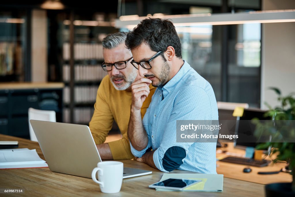 Businessmen using laptop at desk
