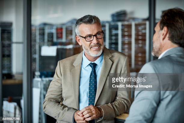 businessman looking at coworker in textile factory - business  imagens e fotografias de stock