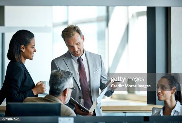 businessman reading documents by colleagues - completo da uomo foto e immagini stock