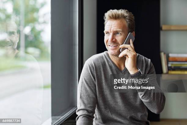 zakenman mobiele telefoon via venster - man sweater stockfoto's en -beelden