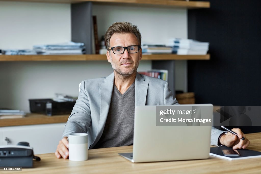 Zuversichtlich Geschäftsmann mit Laptop am Schreibtisch