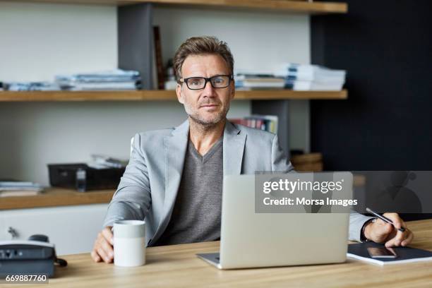 zuversichtlich geschäftsmann mit laptop am schreibtisch - business man at desk stock-fotos und bilder