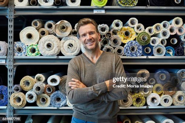 executive with arms crossed against rolled fabric - textile worker stock pictures, royalty-free photos & images