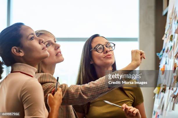 businesswomen looking at fabric samples on board - solo donne foto e immagini stock