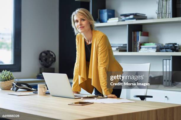 confident businesswoman leaning on desk - fashion for peace stock pictures, royalty-free photos & images