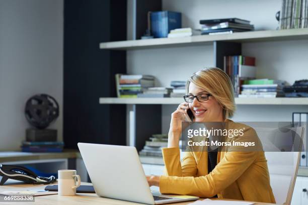businesswoman using laptop and smart phone at desk - desk woman glasses stock pictures, royalty-free photos & images