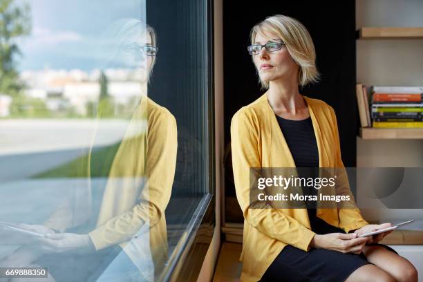 executive met tablet pc op zoek door raam - woman looking out window stockfoto's en -beelden