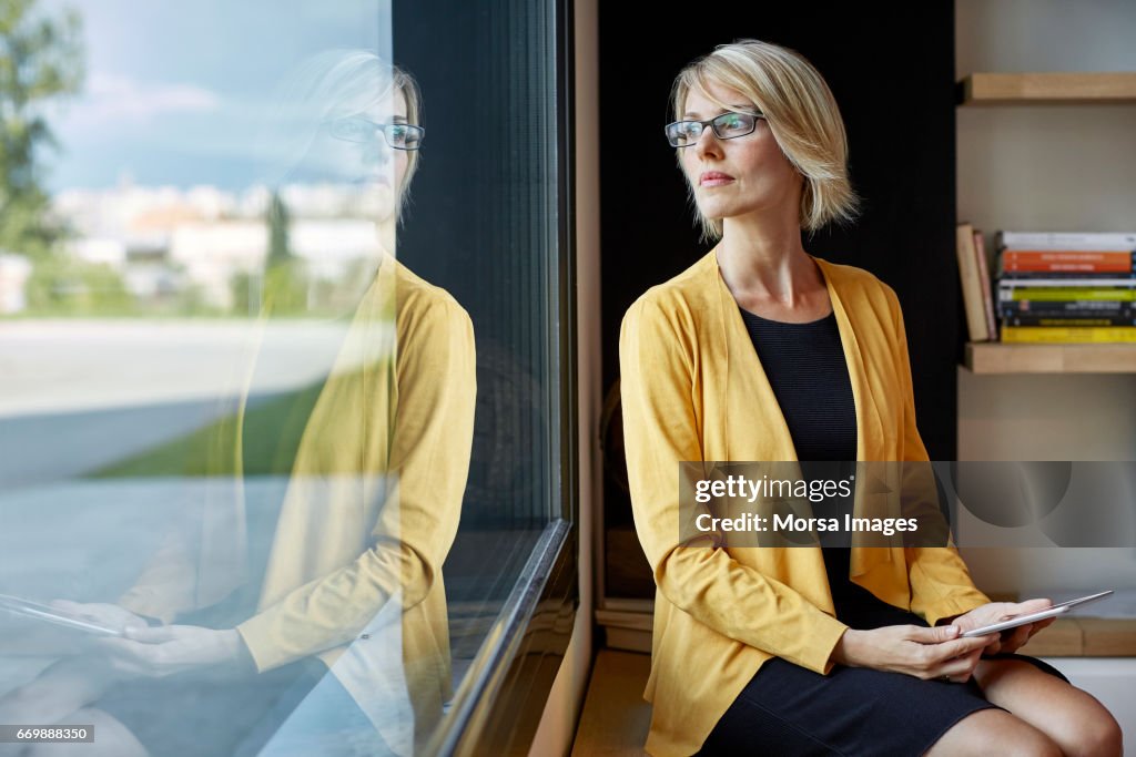 Executive with tablet PC looking through window
