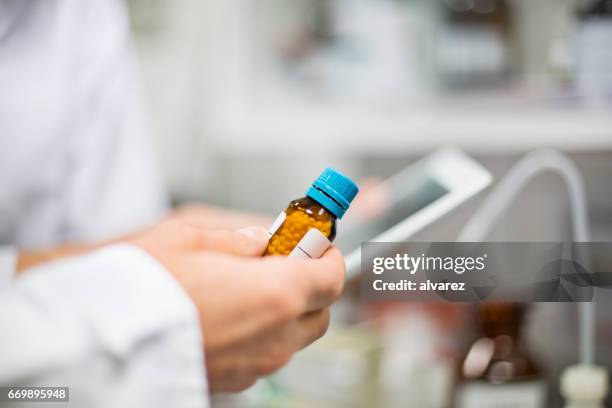 scienziato in possesso di bottiglia di pillola e tablet digitale - omeopatia foto e immagini stock