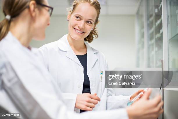 happy scientist looking at colleague in laboratory - doctor side view stock pictures, royalty-free photos & images