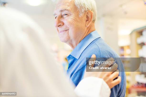 lächelnder senior mann blick auf apotheker - überbelichtet stock-fotos und bilder