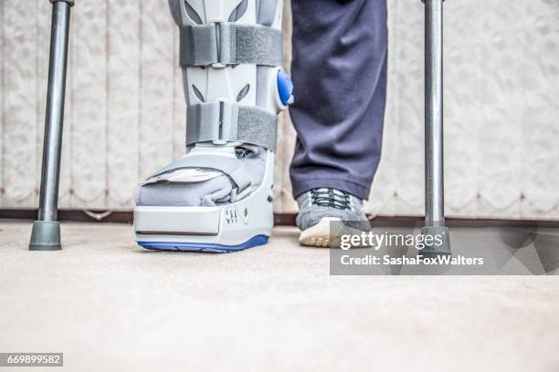 mature woman wearing leg brace and crutches - orthopaedic equipment stock pictures, royalty-free photos & images