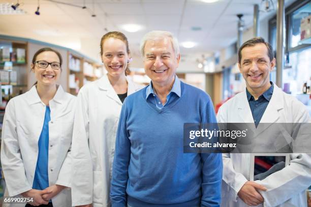 happy pharmacists and senior man in store - pharmacist and patient stock pictures, royalty-free photos & images