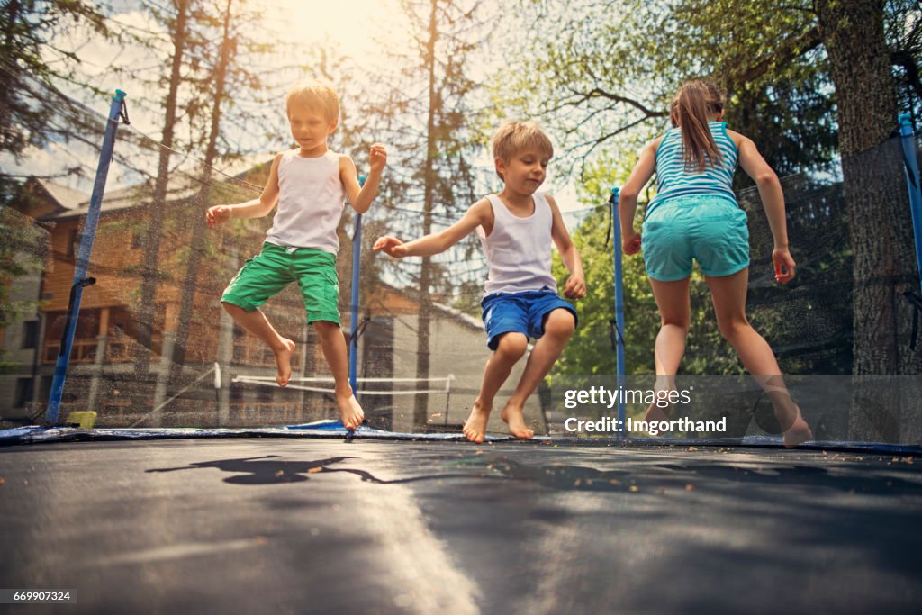 Drei Kinder auf große Trampolin springen