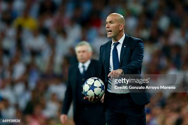 Head coach Zinedine Zidane of Real Madrid CF holds the ball ahead coach Carlo Ancelotti of Bayern Muenchen during the UEFA Champions League Quarter...
