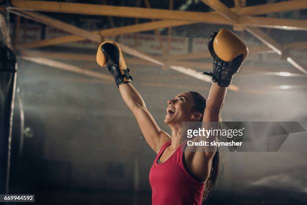 successful female boxer celebrating her victory in a health club. - combat sport stock pictures, royalty-free photos & images