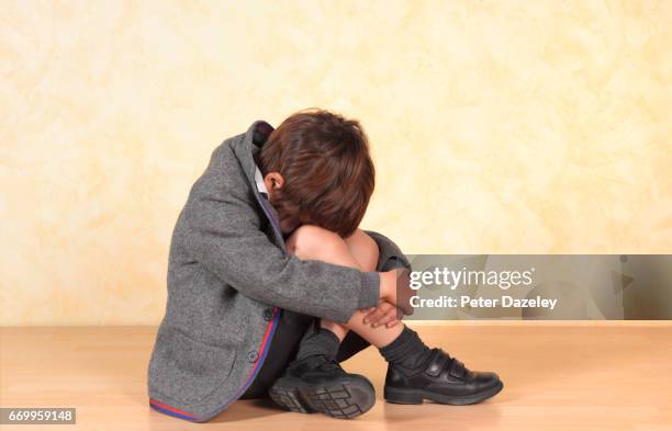 school boy sitting alone a poor child is bullied at school - boy sitting on floor stockfoto's en -beelden