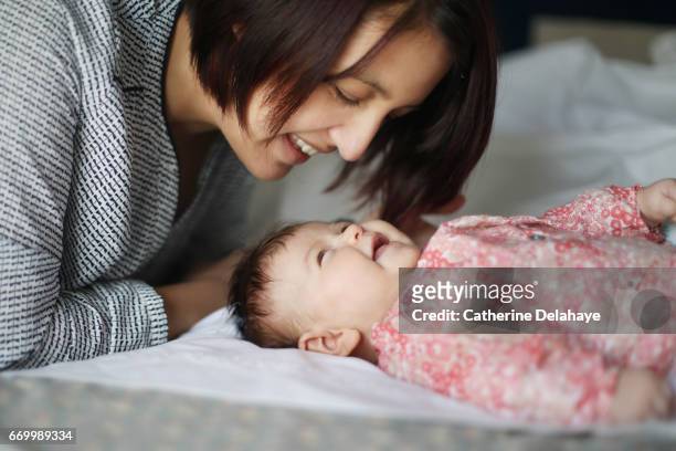 a mom smiling to her 2 months old baby girl - bébé parents stock pictures, royalty-free photos & images