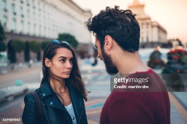 joven pareja discutiendo en la calle - confrontation fotografías e imágenes de stock