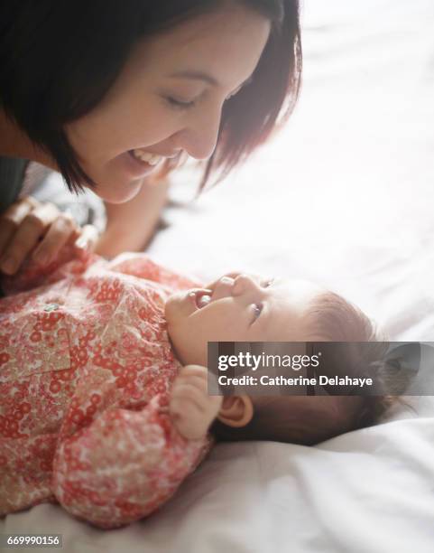 a mom smiling to her 2 months old baby girl - affectueux stock pictures, royalty-free photos & images